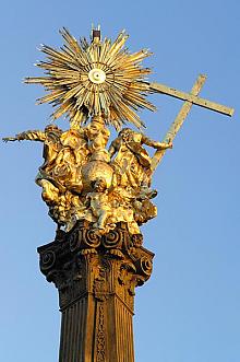 An der Spitze der Säule befinden sich die Statuen der hl. Dreifaltigkeit – im unteren Teil wird die wertvolle Figurengruppe durch die Statue ...